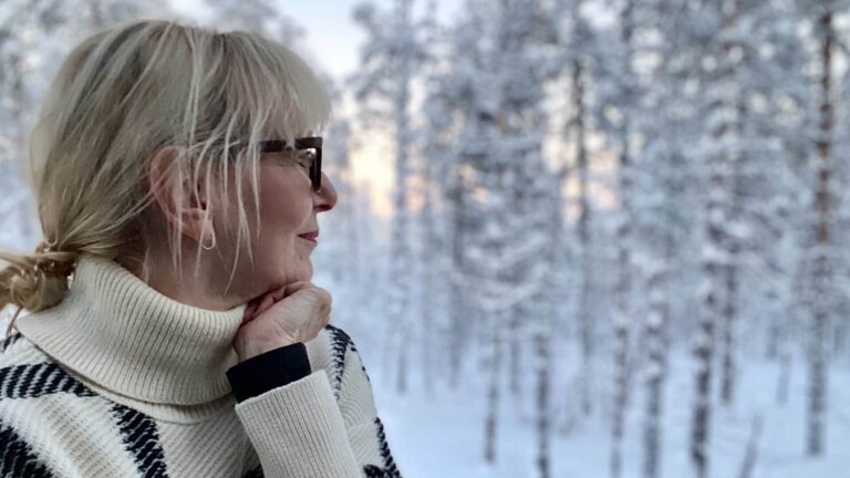 Birgit Elke Ising schaut durch ein Fenster auf verschneite Bäume