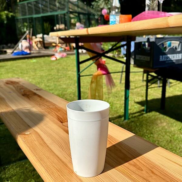 Eine Tasse Kaffee auf einer Bierbank im Garten.